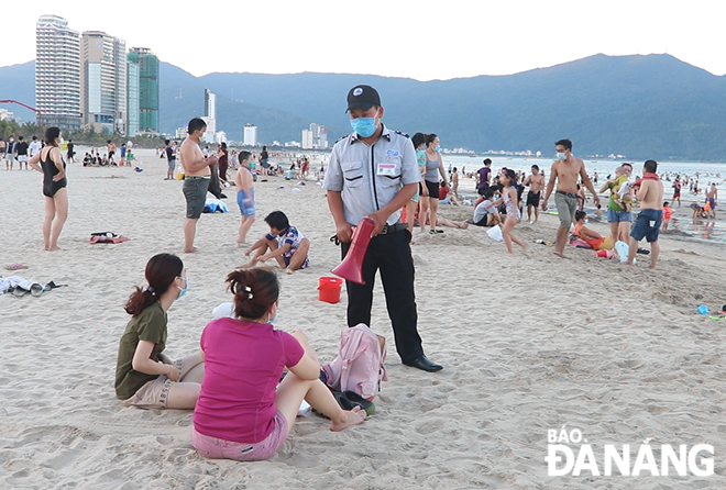 Security guards conduct patrols on beaches to remind people not to eat or drink, to wear masks when they are on the beach. Photo: VAN HOANG