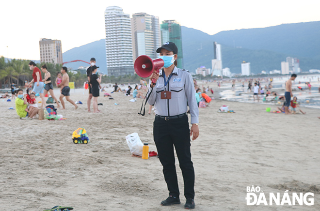 Using a loudspeaker to send reminders to beach-goers to ask them to comply with COVID-19 rules. Photo: MINH LE