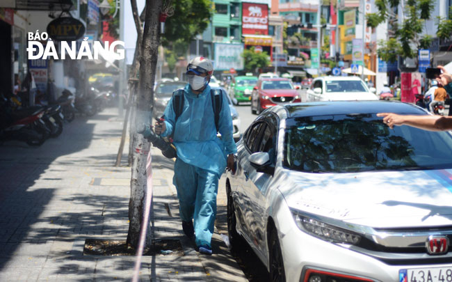 Medical workers carry out disinfectant sprays for the prevention of COVID-19 in the surroundings of the alley 407 in Le Duan Street where many new cases have been detected in the past two days. Photo: PHAN CHUNG