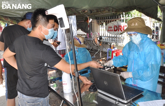 Nhân viên y tế làm nhiệm vụ tại điểm chốt tuyết đường Tạ Quang Bửu giúp tài xế khai báo y tế bằng hệ thống QR code. Ảnh: LÊ HÙNG