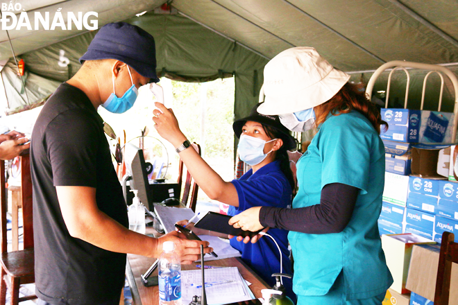 Thanh niên tình nguyện huyện Hòa Vang hỗ trợ đo thân nhiệt cho người dân. Ảnh: THANH TÌNH	