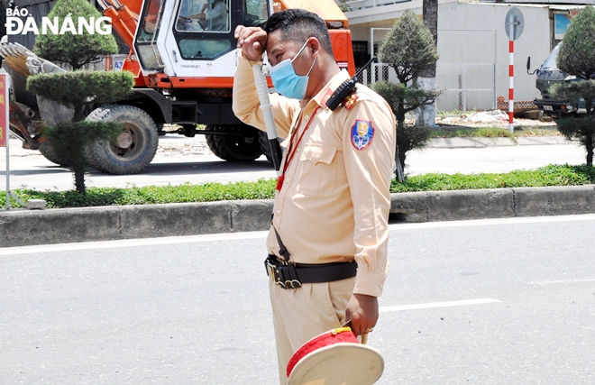  Taking advantage of the absence of traffic, Captain Nguyen Huu Nhat Nam from the Hoa Nhon Traffic Police takes off his hat to wipe sweat out in the sun.