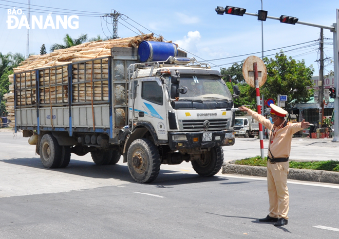 Traffic Police officers on duty at a checkpoint on the National Highway 14B in Hoa Nhon Commune, Hoa Vang District stop a truck to require its driver to declare his heath status and have his body temperature checked.  Photo: LE HUNG