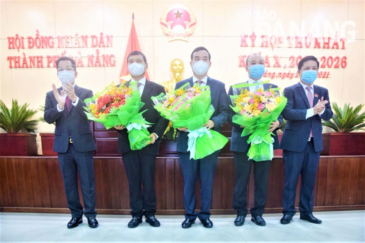 Secretary of the City Party Committee Nguyen Van Quang (left cover) and Chairman of the City Peoples Council Luong Nguyen Minh Triet (right cover) give flowers to congratulate Chairman of the City Peoples Committee Le Trung Chinh (center) and Vice Chairman of the City Peoples Committee, term X Photo: TRUNG HUY