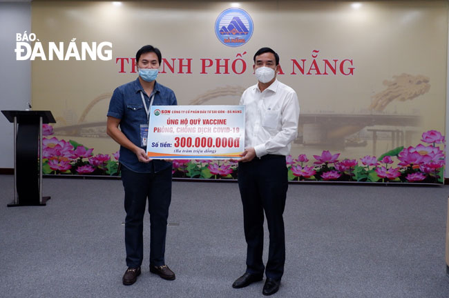 Chủ tịch UBND thành phố Lê Trung Chinh (phải) tiếp nhận số tiền ủng hộ Quỹ vắc-xin thành phố từ Công ty Cổ phần Đầu tư Sài Gòn - Đà Nẵng vào chiều 25-6. Ảnh: PHAN CHUNG