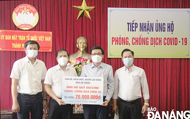 Da Nang Newspaper Editor-in-Chief  Nguyen Duc Nam (second from left) hands over a symbolic board of donations worth VND 20 million to support the city’s COVID-19 Vaccine Fund. Photo: Dac Manh.