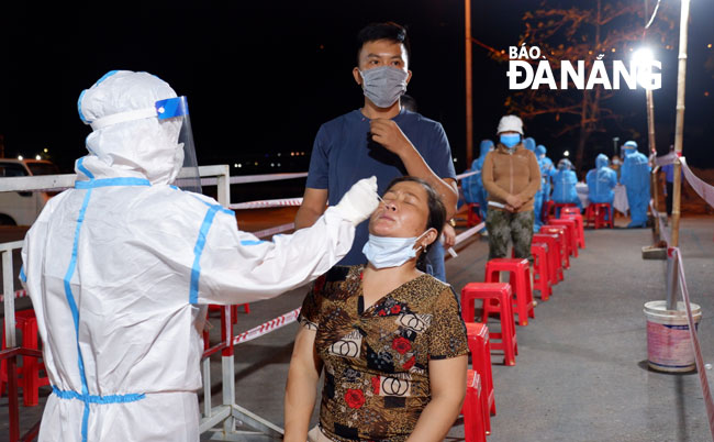 Lực lượng y tế lấy mẫu xét nghiệm SARS-CoV-2 cho tiểu thương tại Cảng cá Thọ Quang khuya 1-7. Ảnh: PHAN CHUNG