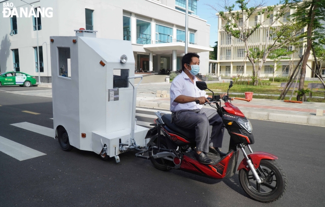 Thầy Đặng Xuân Thuỷ dễ dàng di chuyển cabin chở bệnh nhân bằng kéo tay hoặc xe máy điện. Ảnh: NGỌC HÀ.