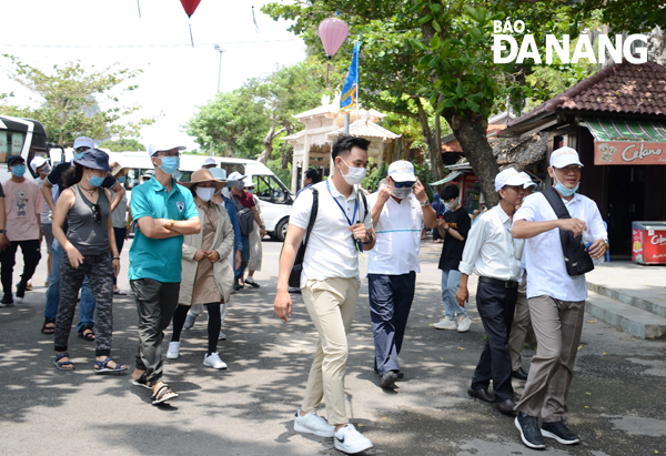 The loan package aims to support tourism workers to get through some difficulties triggered by their job loss. The tour guide (who holds the flag) is guiding the group at the Marble Mountains Tourist Area. (Photo taken before April 30, 2021 by THU HA)