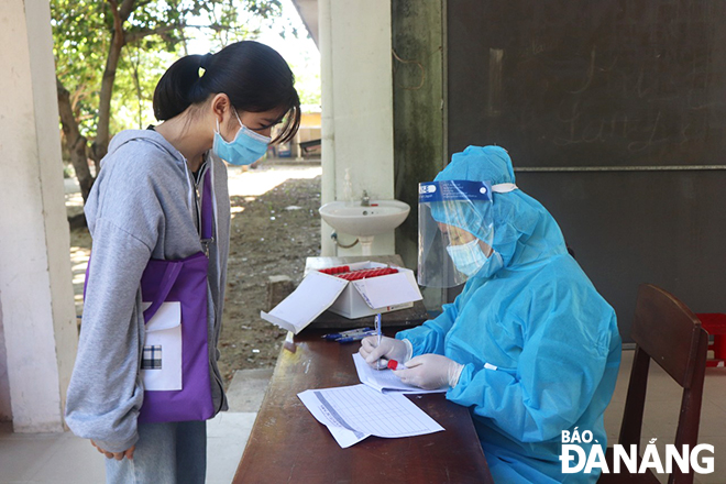 Nhân viên y tế khai thác thông tin cá nhân của thí sinh dự thi tại điểm thi THPT Ngũ Hành Sơn. Ảnh: NGỌC HÀ