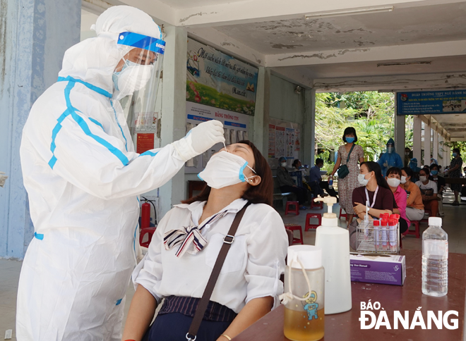 A medical worker takes swab samples of an invigilator to test for the virus at Ngu Hanh Son High School. Photo: NGOC HA