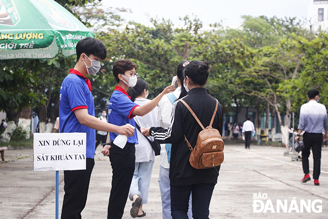 Lực lượng đoàn viên, thanh niên tại Trường THPT Ngô Quyền (quận Sơn Trà) sát khuẩn tay, đo thân nhiệt cho thí sinh trước khi vào điểm thi. Ảnh: XUÂN DŨNG