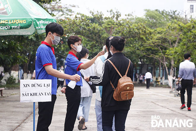 Test takers have their hands disinfected and their body temperatures measured by local Youth Union members before entering the exam venue set at Son Tra District-located Ngo Quyen Senior High School. Photo: XUAN DUNG