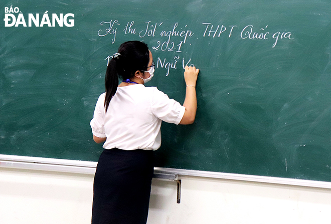  An invigilator recorded exam-related information on the board before calling upon candidates into an exam room at Hai Chau District-based Phan Chau Trinh Senior High School. Photo: NGOC HA 