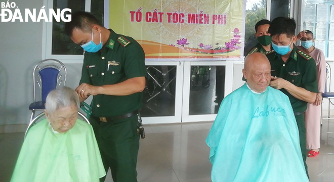 Officers and men of the Da Nang Border Guard give a free haircut to older people staying at the Care Center for people with meritorious services to the revolution. Photo: HONG QUANG