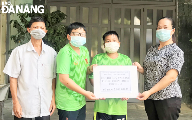 Members of an Environmental Kids Club (middle) hand over their small cash donations to the COVID-19 Vaccine Fund. Photo: LAM PHUONG