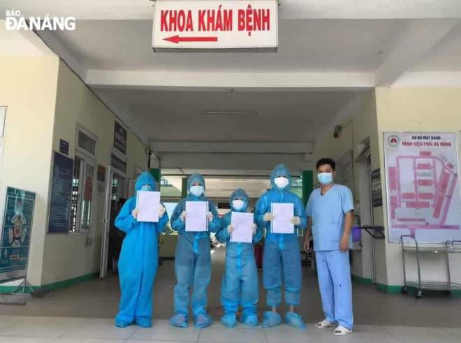 A leader of the Da Nang Lung Hospital and the recovered patients (in blue protective clothing) pose for a photograph before they leave the hospital on Tuesday. Photo: L.H