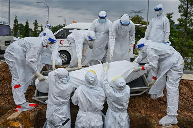 Các tình nguyện viên chôn cất thi thể bệnh nhân COVID-19 tại Kuala Lumpur, Malaysia ngày 15/6/2021. Ảnh: AFP/TTXVN