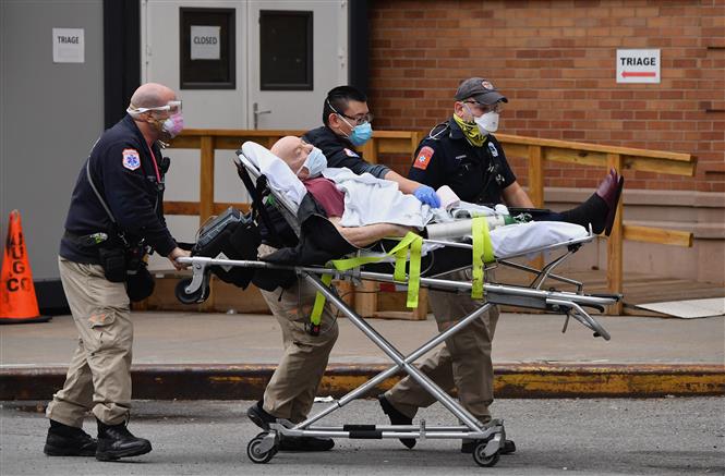 Nhân viên y tế chuyển bệnh nhân COVID-19 vào một bệnh viện ở New York City, Mỹ. Ảnh: AFP/TTXVN