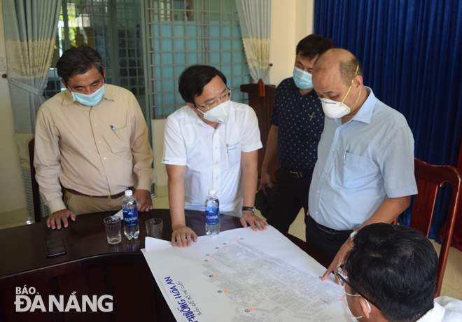 Phó Chủ tịch UBND thành phố Lê Quang Nam (thứ 2 từ phải sang) kiểm tra vị trí các chốt chặn, kiểm soát trên sơ đồ tại phường Hòa An, quận Cẩm Lệ. Ảnh: HOÀNG HIỆP