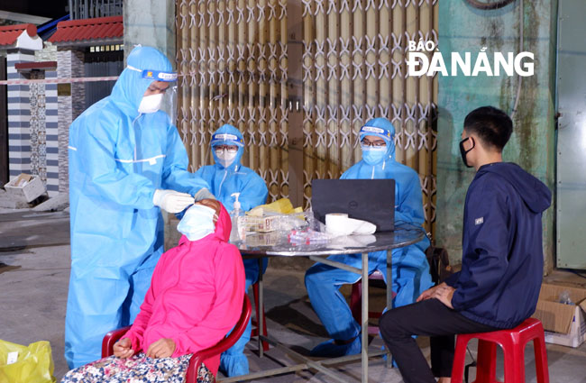 Lực lượng y tế lấy mẫu xét nghiệm SARS-CoV-2 cho người dân phường Hòa Khánh Bắc tối 17-7. Ảnh: PHAN CHUNG