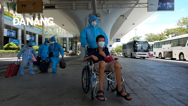 Người gia, người khuyết tật được lực lượng chức năng hỗ trợ di chuyển ra xe chở về khách sạn cách ly. Ảnh: PHAN CHUNG