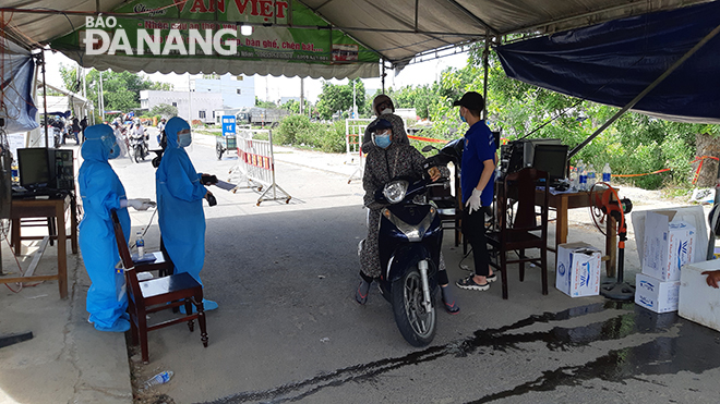 Hướng dẫn người dân kiểm tra thân nhiệt tại Trạm kiểm soát Quốc lộ 1A (gần Trạm CSGT Hòa Phước), huyện Hòa Vang. Ảnh: THÀNH LÂN