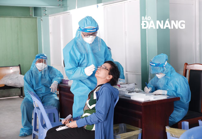 Để bảo đảm an toàn và tránh lây nhiễm chéo, người dân được nhân viên y tế lấy mẫu xét nghiệm SARS-CoV-2.