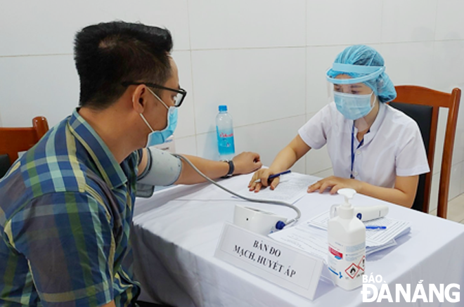 A medical worker measures the blood pressure of a reporter before he receives the COVID-19 vaccine. Photo: PHAN CHUNG