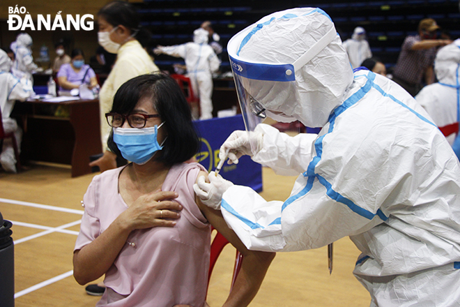 A healthcare professional wearing personal protective equipment from Hai Chau District Medical Centre gave a vaccine to a woman in a mask on July 29. Photo: XUAN DUNG.
