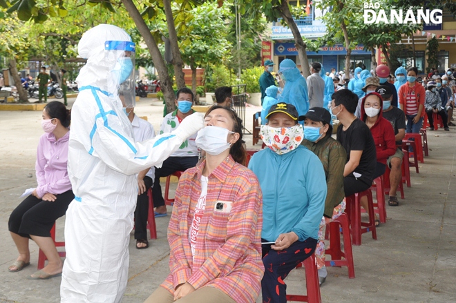 The health agency is urged to roll out mass testing program across the city. In the photo: Health workers from the Son Tra District Medical Center conducting COVID-19 sample collection from a household representative in Man Thai Ward. Photo: LE HUNG