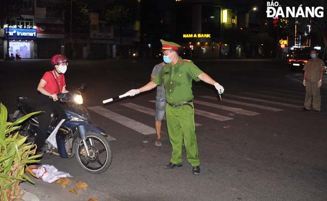 Lực lượng Công an phường Thanh Khê Đông (quận Thanh Khê) hướng dẫn người dân vào điểm chốt để xuất trình giấy đi đường. Ảnh: LÊ HÙNG