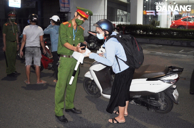 Lực lượng làm nhiệm vụ tại điểm chốt trên tuyến đường Điện Biên Phủ hướng dẫn người dân xin giấy đi đường theo mẫu của UBND thành phố đã ban hành. Ảnh: LÊ HÙNG