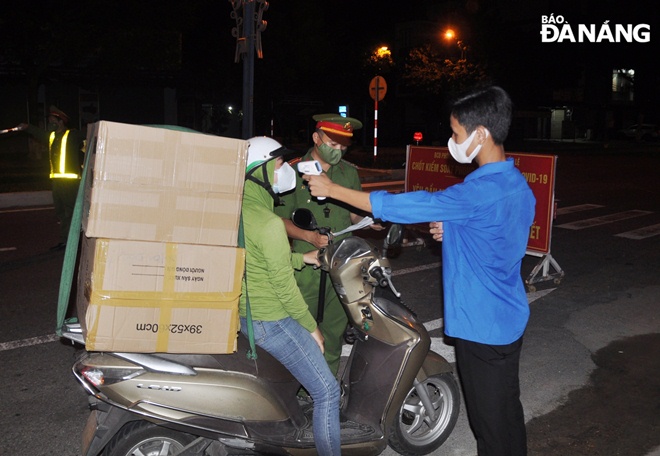 Bên cạnh kiểm tra giấy đi đường, lực lượng làm nhiệm vụ tại điểm chốt trên tuyến đường Lê Đại Hành (quận Cẩm Lệ) cũng kiểm tra thân nhiệt đối với người dân. Ảnh: LÊ HÙNG