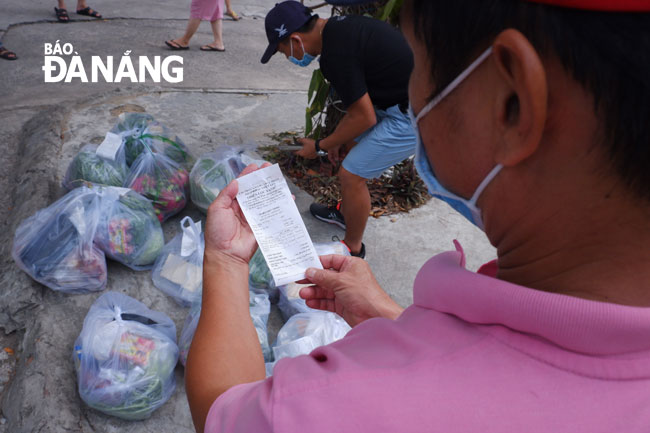 The volunteers carefully re-check lists of food items before giving them to families. Photo: PHAN CHUNG