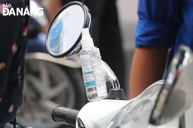 Many motorbike riders bring along a hand sanitizer to protect themselves from COVID-19. Photo: Xuan Dung