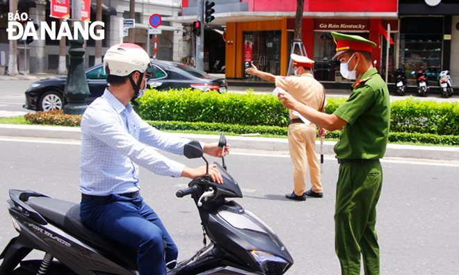 A police officer stops a motorbike rider to check his valid reason for leaving home at a checkpoint on Nguyen Van Linh in Hai Chau District. Photo: Xuan Dung