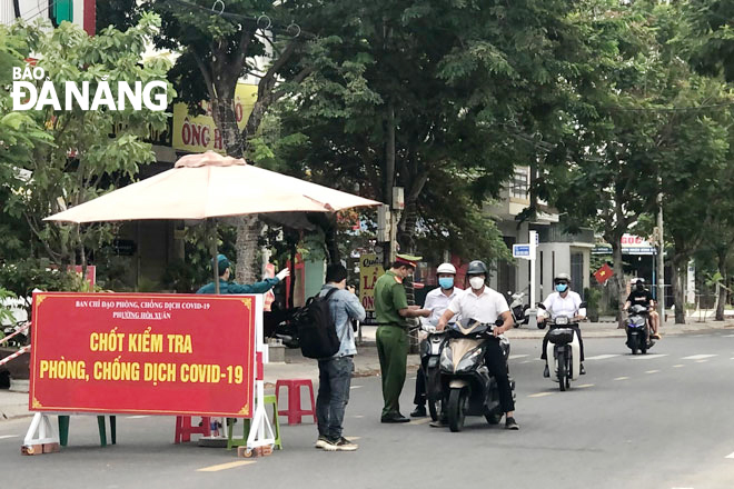 Lực lượng chức năng kiểm tra giấy đi đường của những người di chuyển qua chốt  kiểm soát dịch tại ngã tư đường Nguyễn Quang Diêu - Đinh Gia Trinh (phường Hòa Xuân, quận Cẩm Lệ). Ảnh: NGUYỄN QUANG