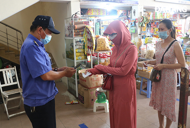 Market-goers to the Dong Da Market present the QR code entry cards to guards for their entry. Photo: VAN HOANG