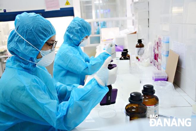 Medical staffers conduct the analysis of samples collected from the direct contacts for COVID-19 testing. Photo: LE HUNG