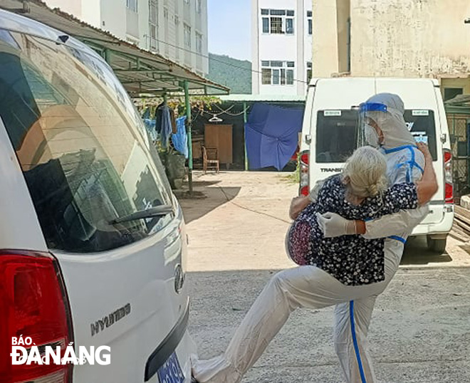 Senior Lieutenant Nguyen Thanh Binh carries the elderly COVID-19 patient from the 4th floor of the concentrated quarantine area. PHOTO: TONG KHIEM