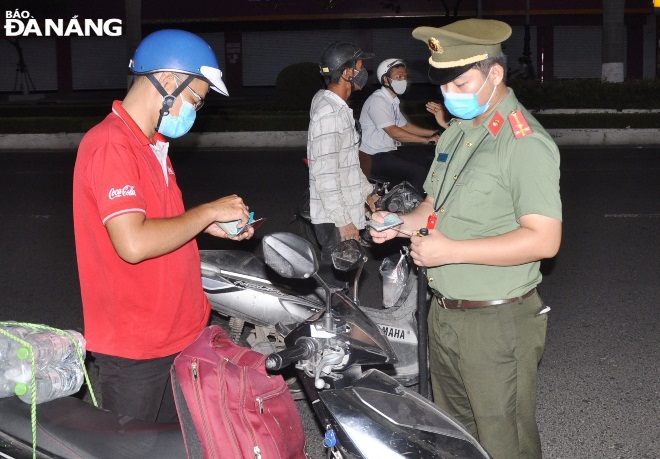 The taskforce at the checkpoint on Dien Bien Phu Street stops a motorbike rider to check his travel permit. Photo: LE HUNG