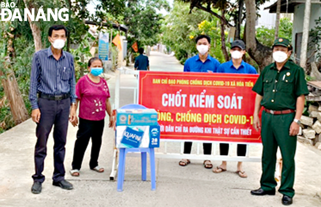 Cựu chiến binh (bên phải) tham gia làm nhiệm vụ tại chốt kiểm soát phòng, chống Covid-19 trên tuyến đường đi qua thôn Lệ Sơn Nam, xã Hòa Tiến (huyện Hòa Vang). Ảnh chụp ngày 4-8-2021. Ảnh: LÊ VĂN THƠM