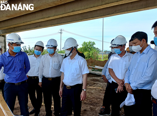 Bí thư Thành ủy Nguyễn Văn Quảng (thứ tư bên trái sang) nghe báo cáo thực tế thi công tại hiện trưởng đối vưới dự án Tuyến đường Vành đai phía tây. Ảnh: TRIỆU TÙNG.