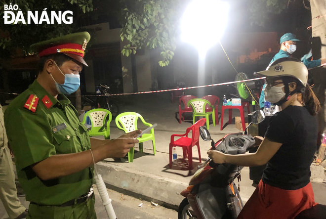 Đại úy Lê Tấn Dũng (trái) kiểm tra giấy đi đường tại khu vực chốt Nguyễn Huy Tưởng, quận Liên Chiểu.Ảnh: V.T