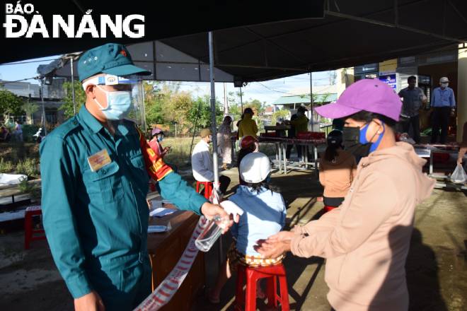 Before buying food items, shoppers are required to disinfect their hands and provide their personal information for taskforce staffing at food selling points. Photo: QUYNH TRANG