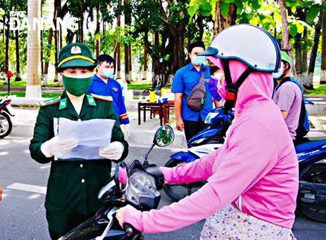 Thiếu tá Nguyễn Thị Mỹ Hạnh (bìa trái) làm nhiệm vụ kiểm tra giấy đi đường tại chốt kiểm soát tuyến đường Nguyễn Tri Phương, quận Thanh Khê	