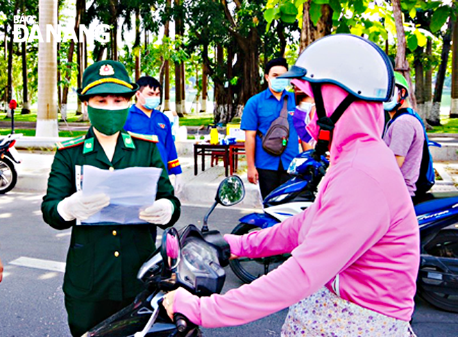 Reporting by PHAM VAN HUNG- Translating by T.VY  Major Nguyen Thi My Hanh (first, left) is in charge of checking travel permits at Nguyen Tri Phuong checkpoint in Thanh Khe District.