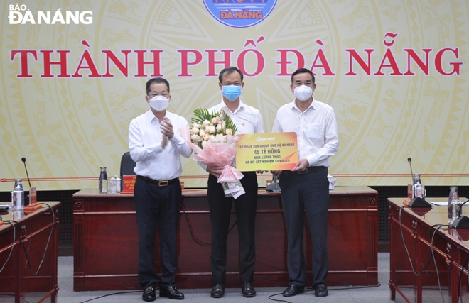 Da Nang Party Committee Secretary Nguyen Van Quang (left) and municipal People's Committee Chairman Le Trung Chinh (right) receive the symbolic board of the cash donation from the representative of Sun Group (middle), August 15, 2021. Photo: LE HUNG