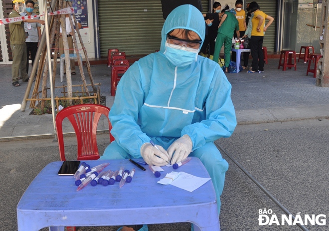 Mr. Tran Ngoc Ut, the Principal of Ho Nghinh Junior High School in Hoa Cuong Nam Ward, Hai Chau District serves as a volunteer at a sampling point with the task of recording locals’ information on sample tubes, August 16, 2021 Photo: LE HUNG